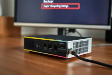 alt_text: A USB drive is inserted into a modern set-top box on a wooden desk, with a monitor in the background confirming a backup process.